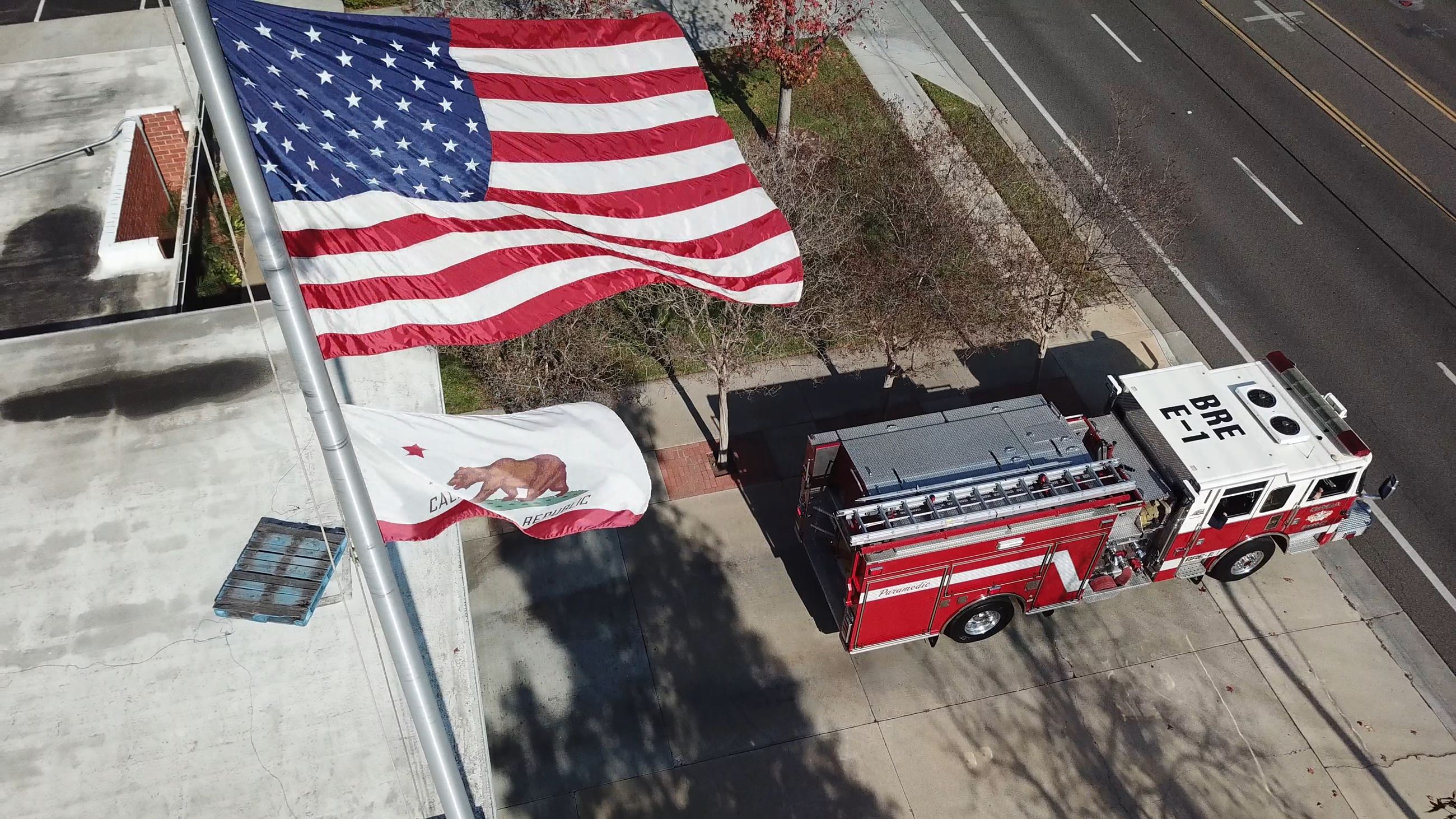 Fire engine rolling out of fire station one with the American Flag waving in the foreground